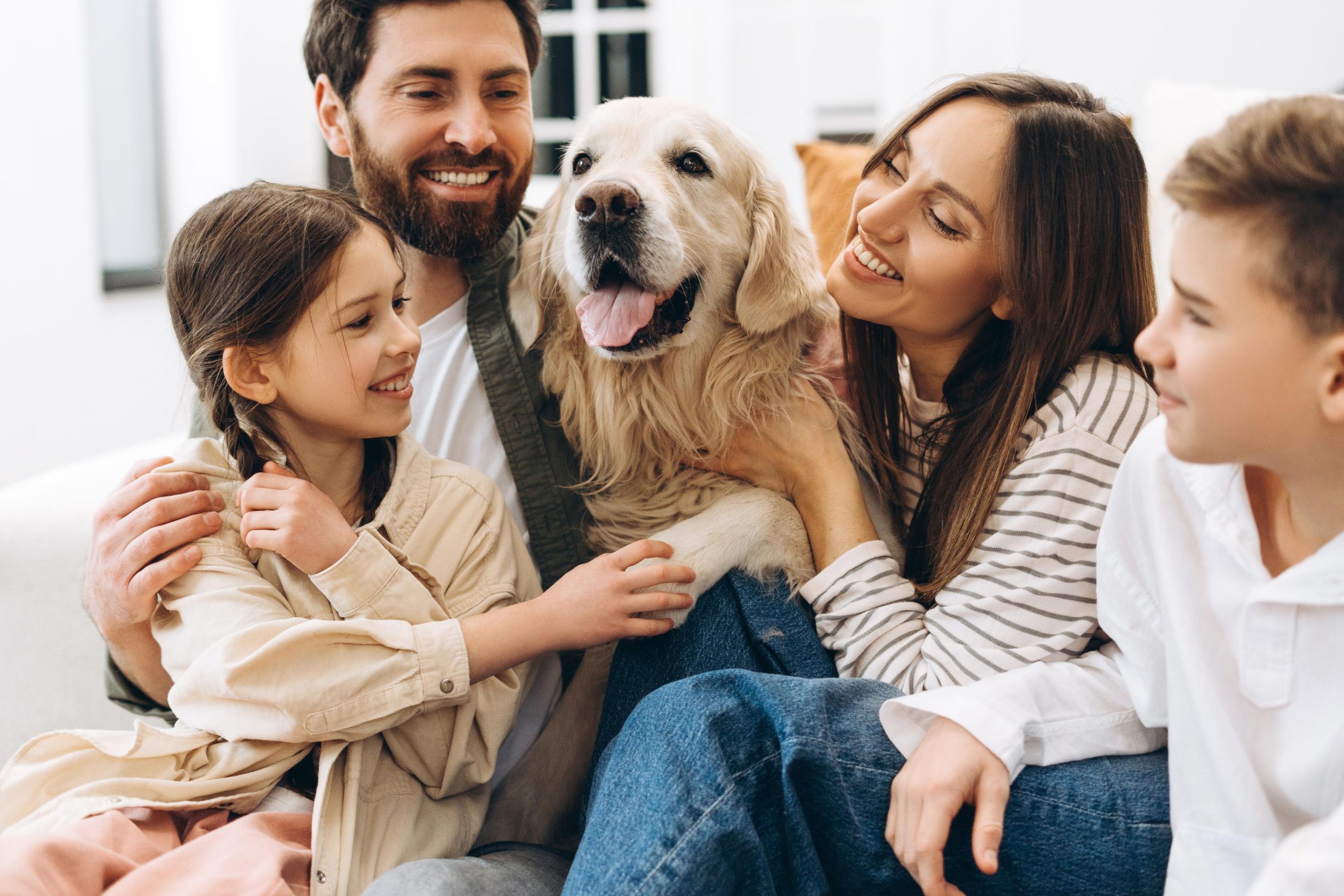 Happy family embracing golden retriever at home