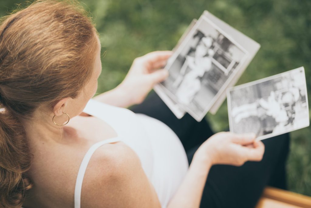 pregnant woman sitting on the bench and loocking сhildren's pho