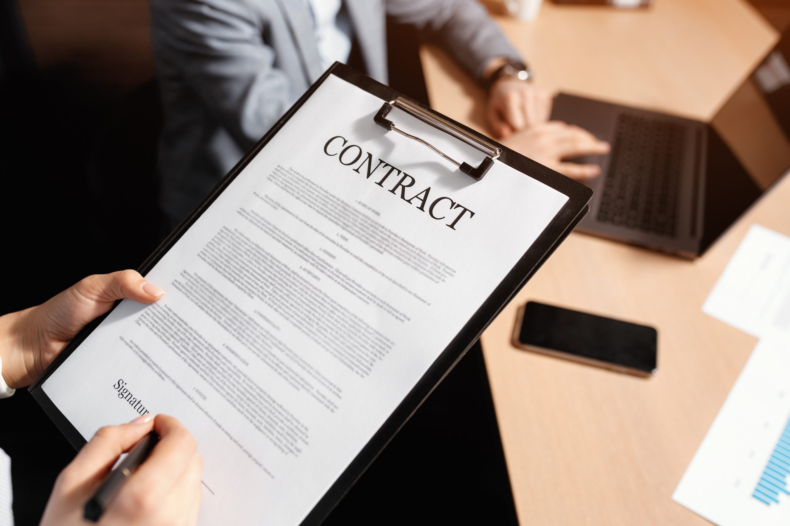 Close-up photo of business woman and man signing a contract in moden office