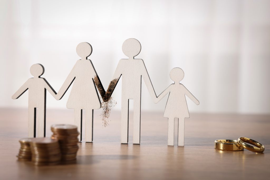 Alimony. Figures of family, coins and wedding rings on wooden