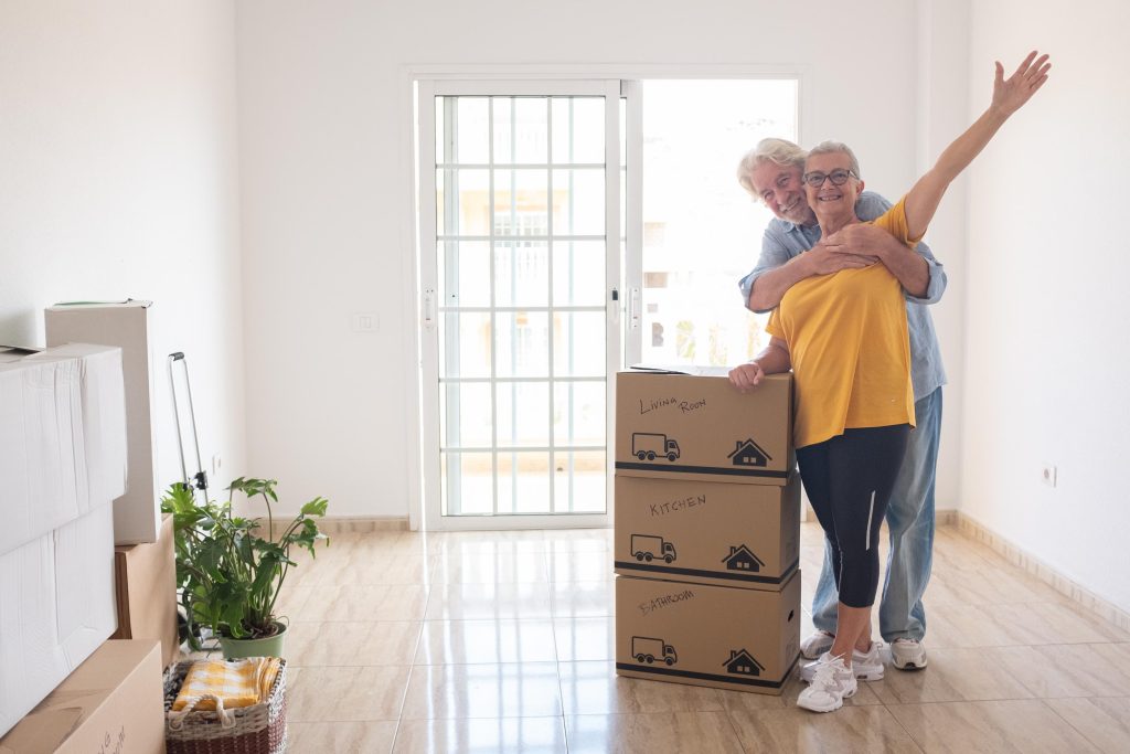 Cheerful senior couple enjoys moving into a new home, surrounded