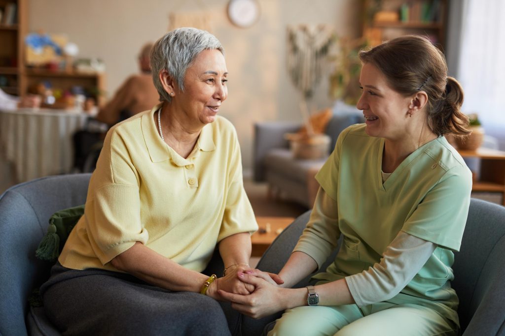 Senior Woman Bonding with Female Caregiver in Nursing Home
