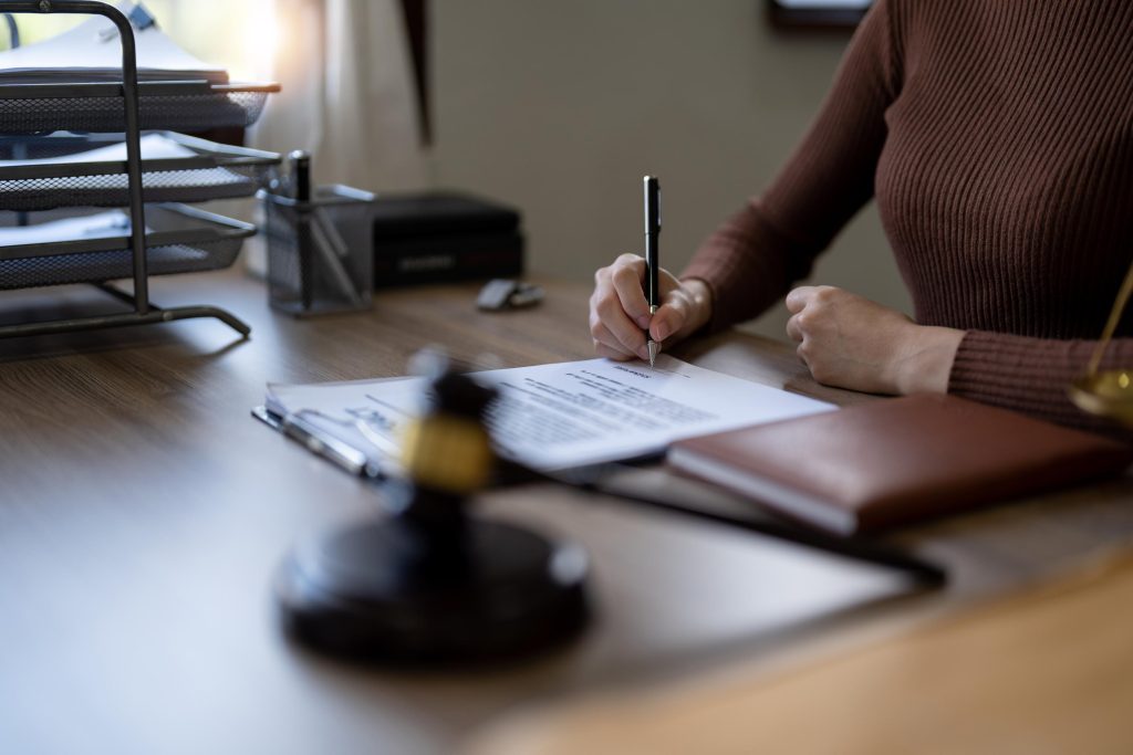 Close up business female hands holding pen, signing in white paper form or application to confirm and deal contract agreement on table