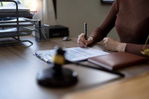 Close up business female hands holding pen, signing in white paper form or application to confirm and deal contract agreement on table