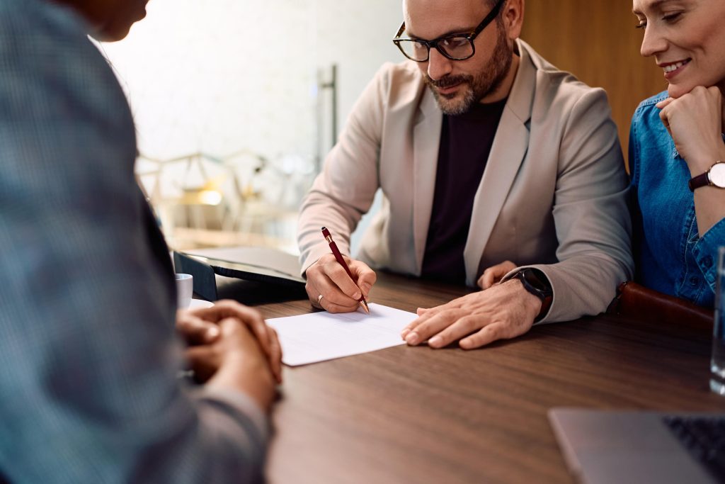 Business Professional Signs Documents with Colleagues in Office