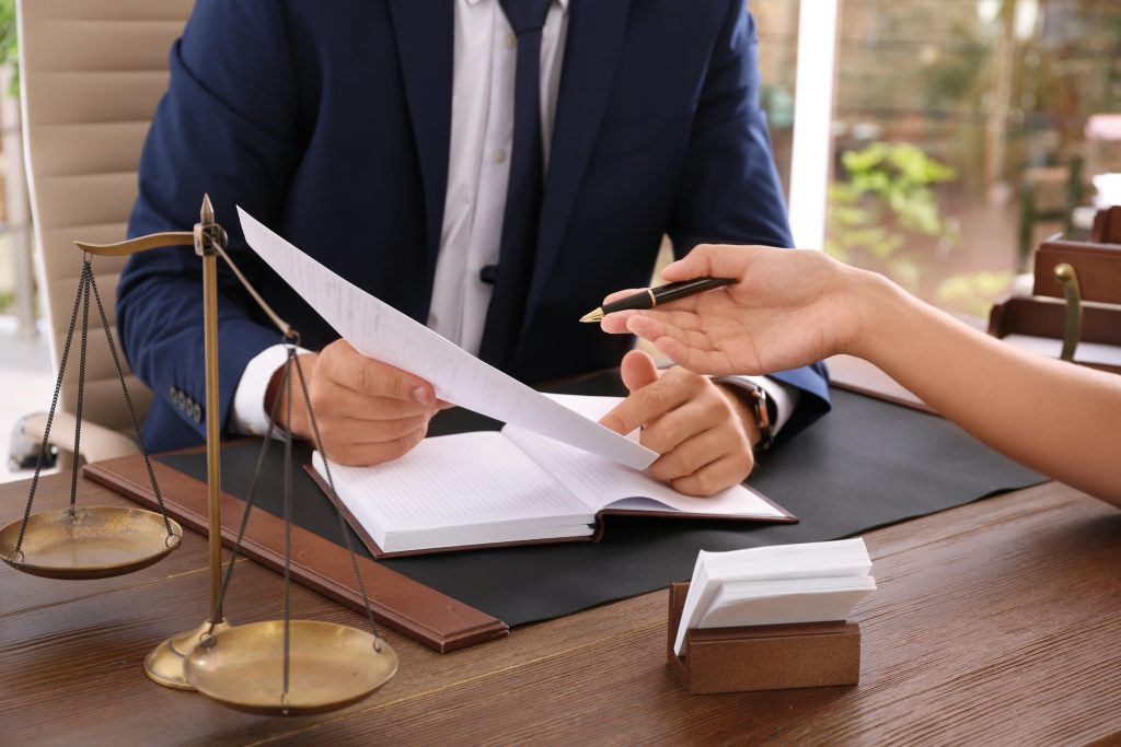Lawyer working with client at table in office, focus on hands